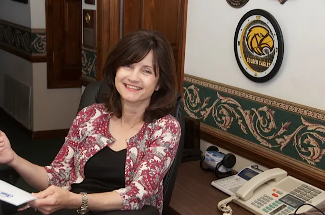 A woman sitting at her desk in front of a phone.